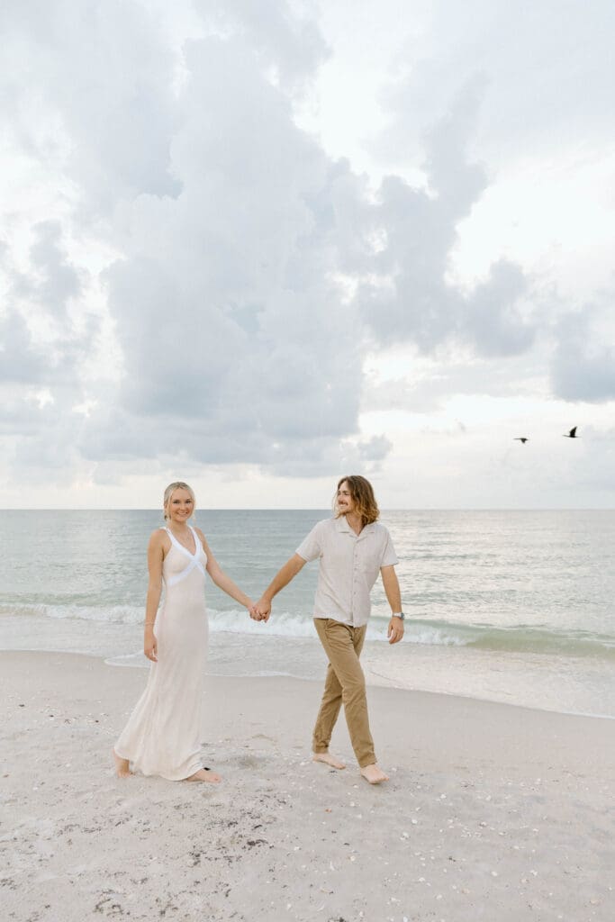 Richie and Meghan walking hand in hand along the beach during their Naples engagement session