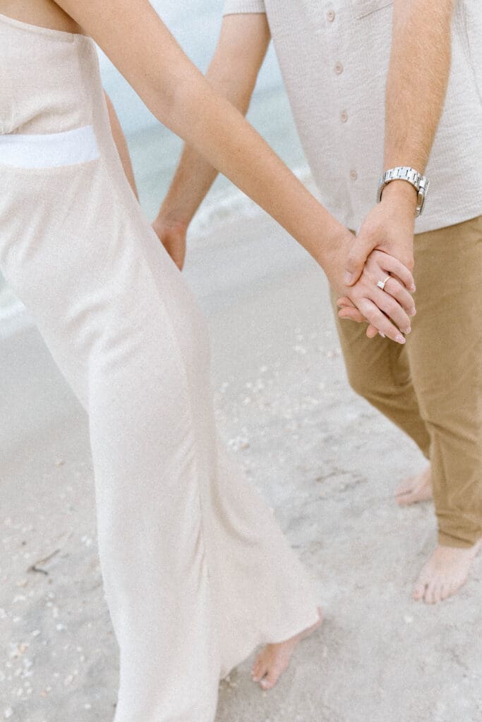 Close-up of Richie and Meghan holding hands with the ocean waves in the background