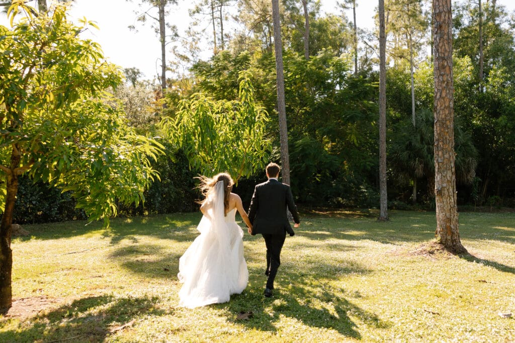 Newlyweds walking through lush greenery at private residence Naples Florida wedding