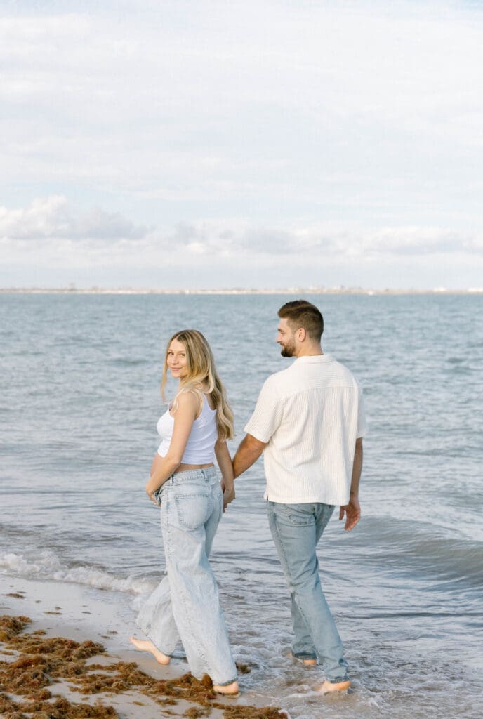 sanibel island maternity photos couple walking barefoot on beach