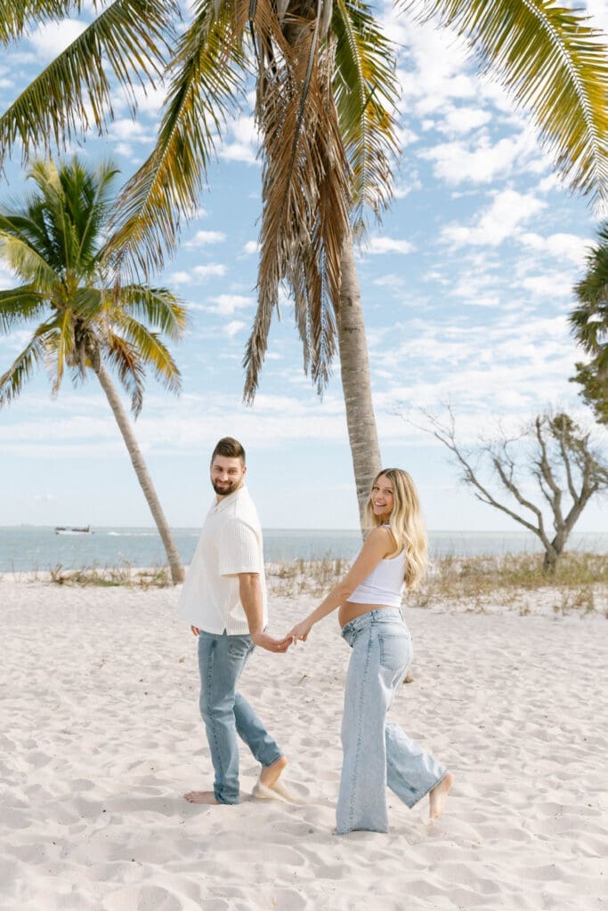 florida beach maternity session couple holding hands at sunset