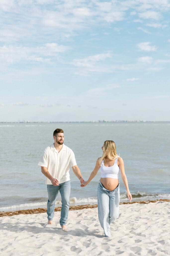 sanibel island maternity photos couple walking barefoot on beach