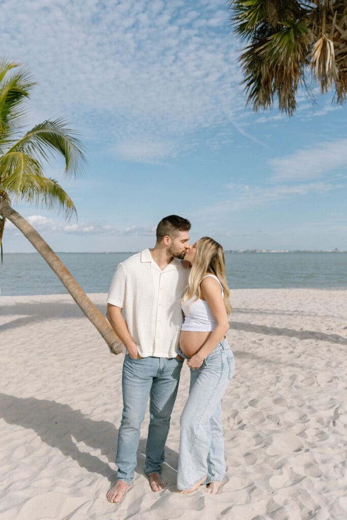 romantic maternity photos beach couple embracing ocean background