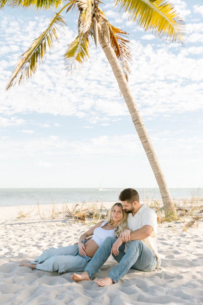 romantic maternity photos beach couple embracing ocean background