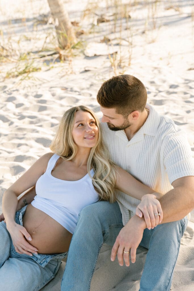 natural maternity photos florida couple walking shoreline barefoot