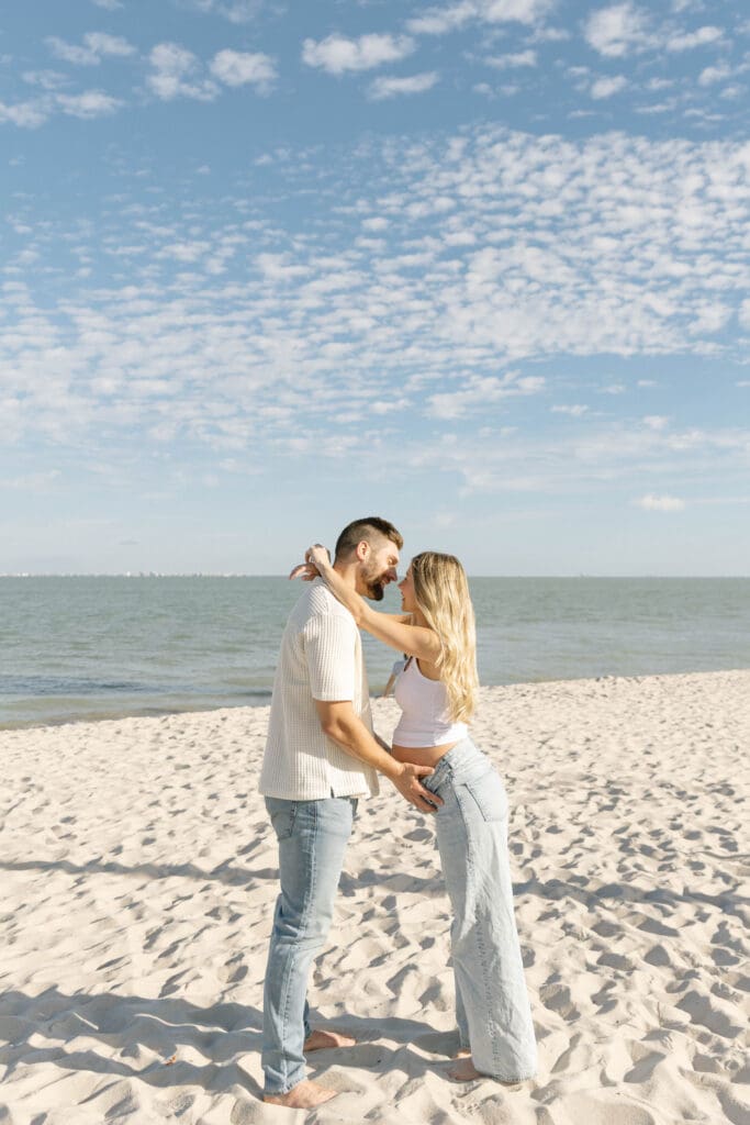 romantic maternity photos beach couple embracing ocean background
